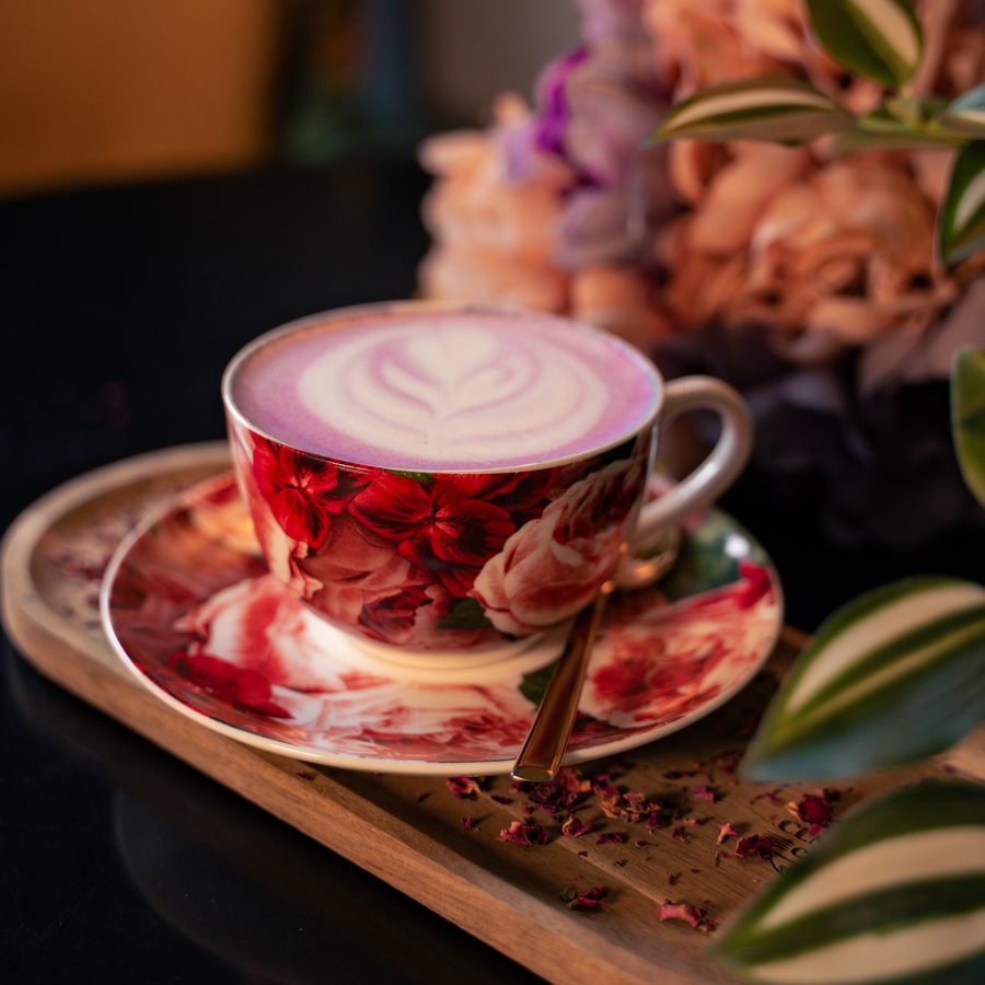 Latte s mliečnym vzorom v kvetinovej šálke na drevenom podnose v Central Caffe v Dubnici nad Váhom